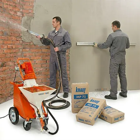 Машинная штукатурка стен: процесс нанесения и выравнивания Двое рабочих выполняют механизированную штукатурку кирпичной стены с помощью штукатурной станции и смеси Knauf MP 75.